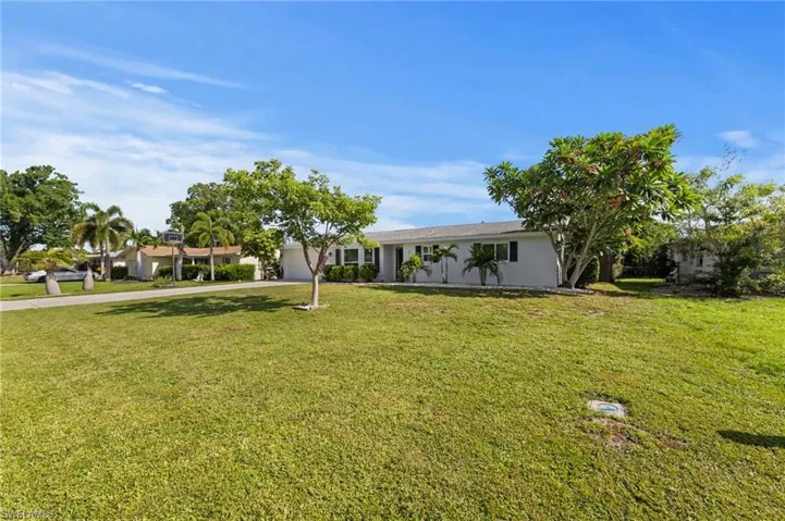 Expansive manicured lawn with mature shade trees and tropical landscaping