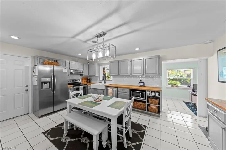 Kitchen featuring stainless steel appliances, grey cabinetry, wood-finish countertops, and white subway tile backsplash