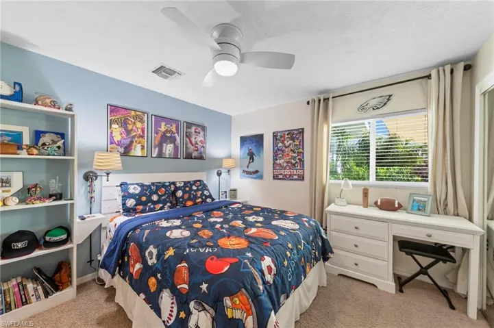 Recessed window with blinds and drapes, ceiling fan with integrated lighting, wall-to-wall carpeting, and a built-in shelving unit