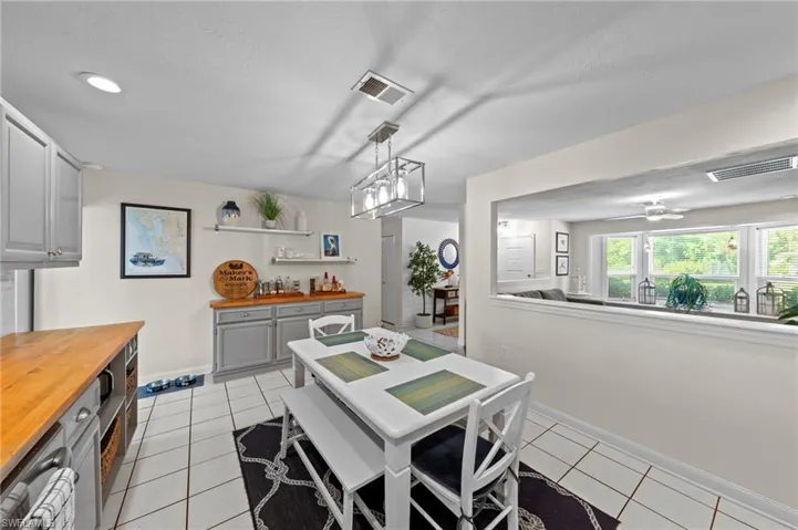 White tile flooring, recessed lighting, built-in cabinetry, and a pass-through window