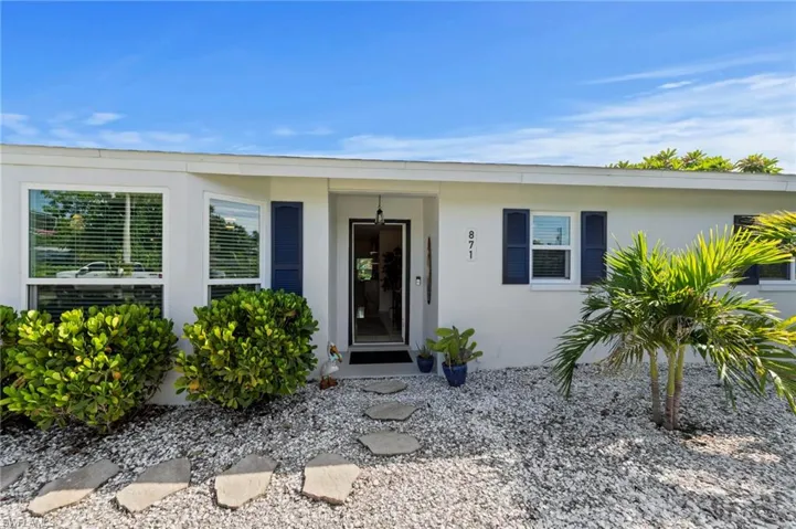White exterior with blue shutters, a clear entry door, and a stone path leading to the entrance