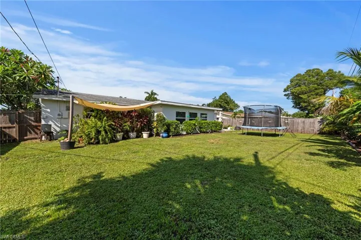Expansive grassy yard area with mature perimeter landscaping and a privacy fence