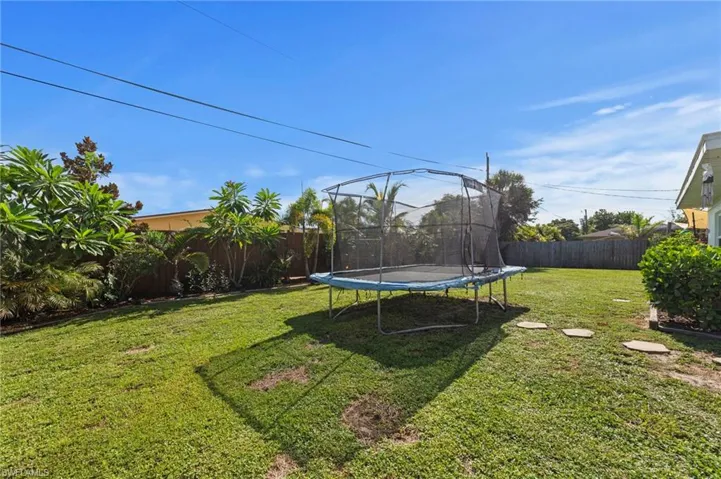 Expansive grassy yard area with mature perimeter landscaping and a privacy fence