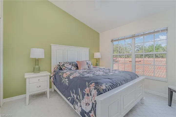 Guest bedroom with high vaulted ceiling, ceiling fan, and light colored carpet