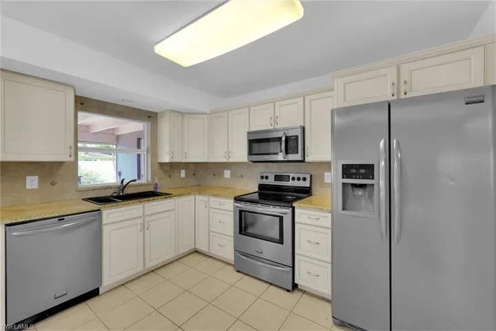 Kitchen featuring appliances with stainless steel finishes, cream cabinets, and backsplash