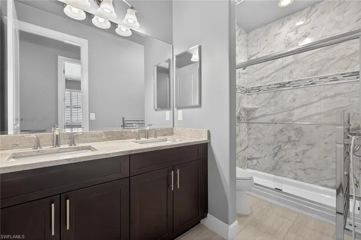 Dual bedroom guest bath with double bowl sink, walk-in shower and towel warmer