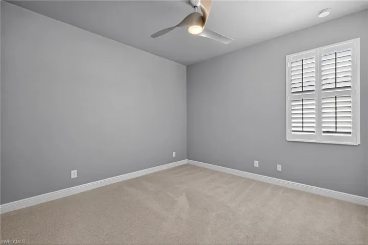 Guest bedroom with plantation shutters, carpeting and ceiling fan