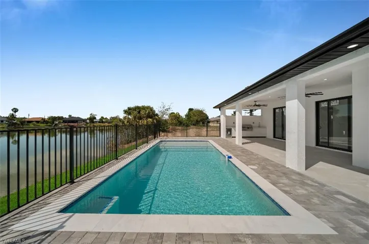 View of swimming pool with a patio area, ceiling fan, and a water view