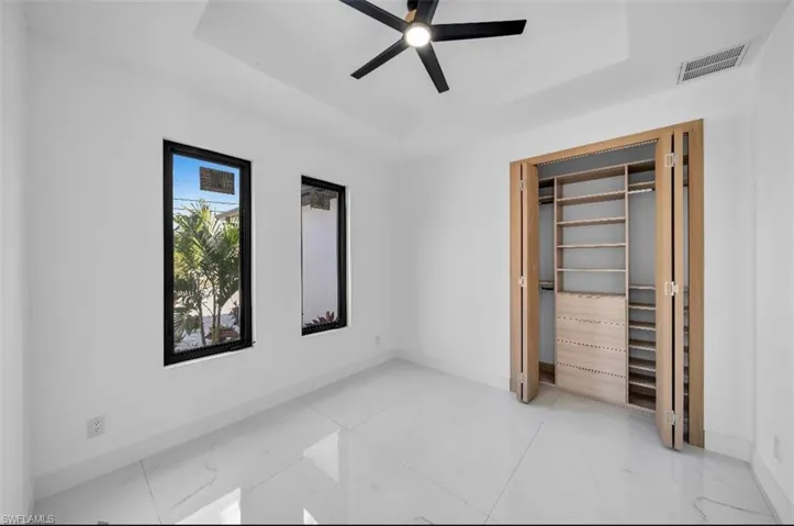 Unfurnished bedroom featuring a tray ceiling and ceiling fan