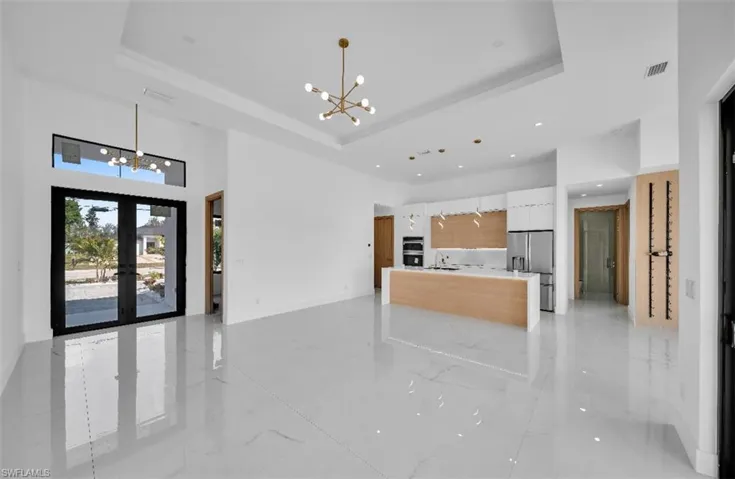 Kitchen with an inviting chandelier, white cabinetry, stainless steel appliances, a tray ceiling, and decorative light fixtures