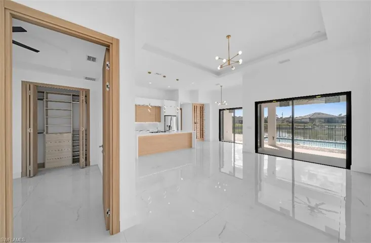 Hallway featuring a high ceiling, a tray ceiling, a chandelier, and a water view