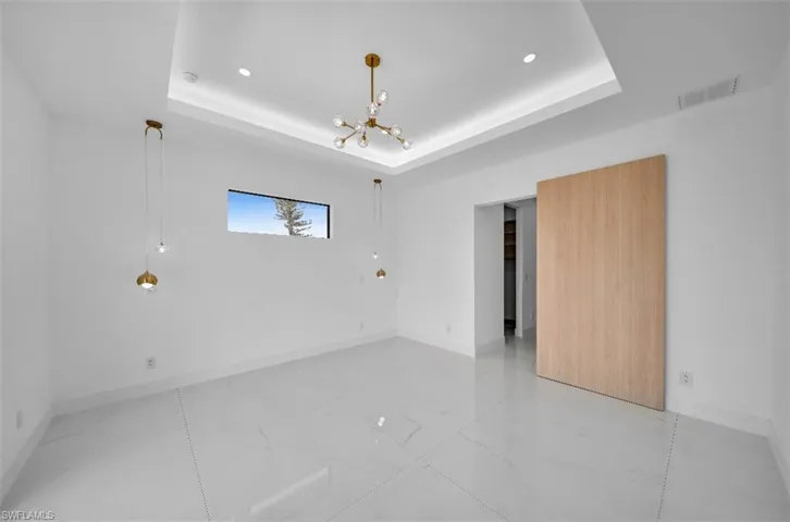 Spare room featuring an inviting chandelier and a tray ceiling