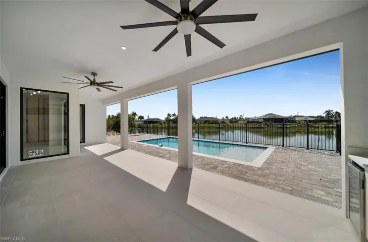 View of swimming pool with a water view, ceiling fan, and a patio