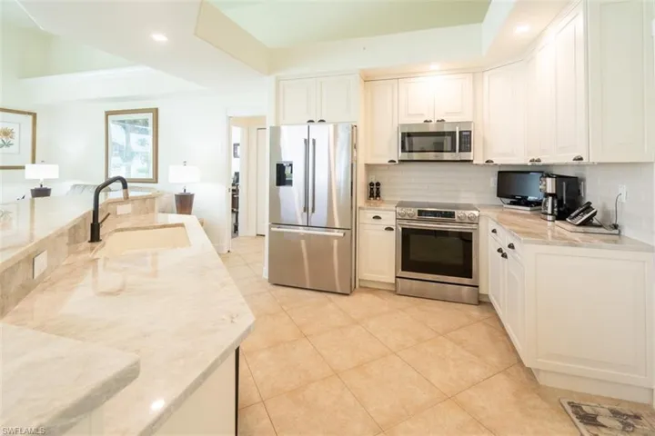 Kitchen with sink, white cabinets, stainless steel appliances, and backsplash