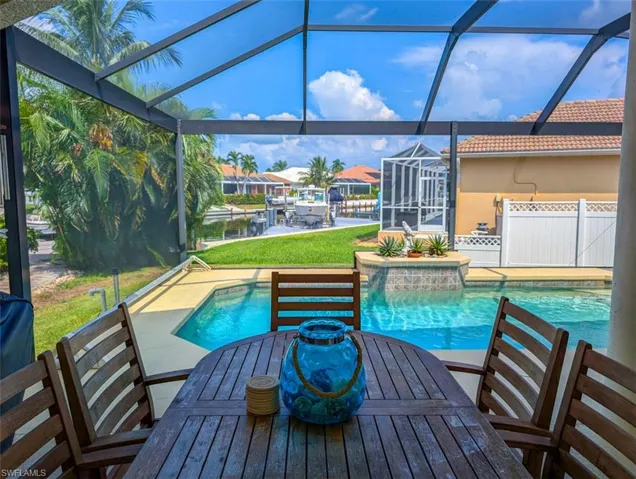 View of pool featuring a patio area, a water view, and glass enclosure