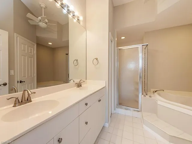 Bathroom featuring tile patterned floors, ceiling fan, shower with separate bathtub, and vanity