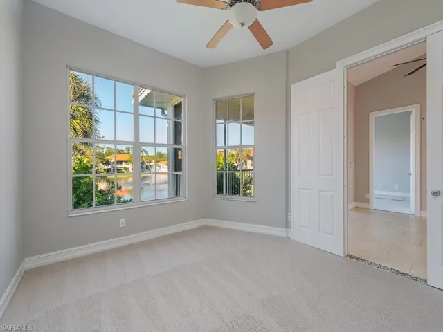 Carpeted spare room with ceiling fan and lofted ceiling