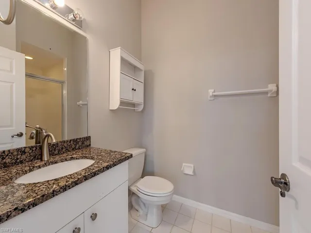 Bathroom featuring toilet, vanity, tile patterned floors, and an enclosed shower
