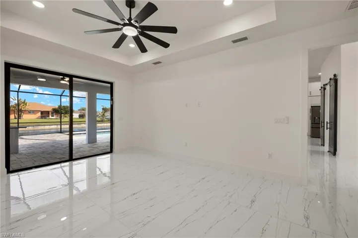 Spare room featuring a tray ceiling, a barn door, and ceiling fan
