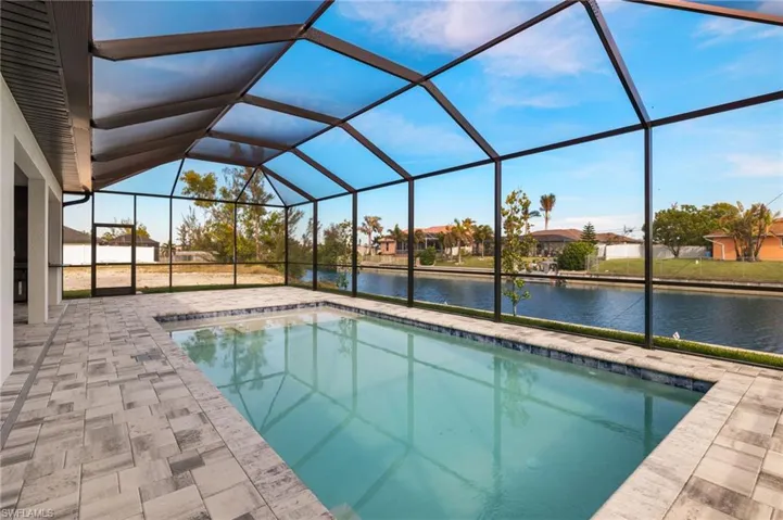 View of swimming pool with glass enclosure, a water view, and a patio