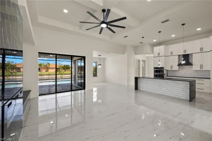Kitchen with white cabinets, ceiling fan, pendant lighting, and wall chimney range hood