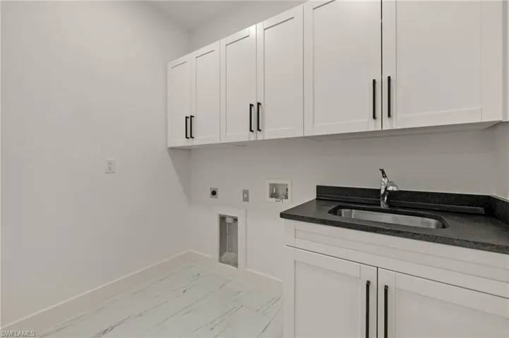 Washroom featuring cabinets, hookup for a washing machine, hookup for an electric dryer, and sink