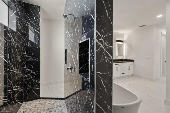 Bathroom featuring plus walk in shower, vanity, and tile walls