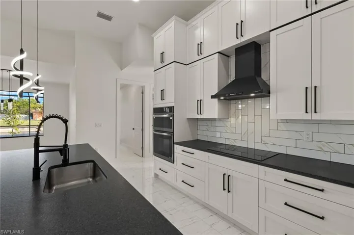 Kitchen featuring white cabinetry, sink, wall chimney exhaust hood, backsplash, and black electric stovetop