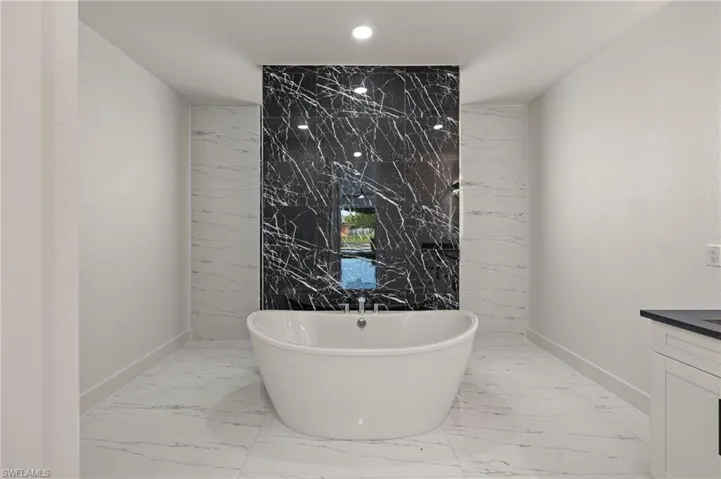 Bathroom featuring vanity, a bath, and tile walls