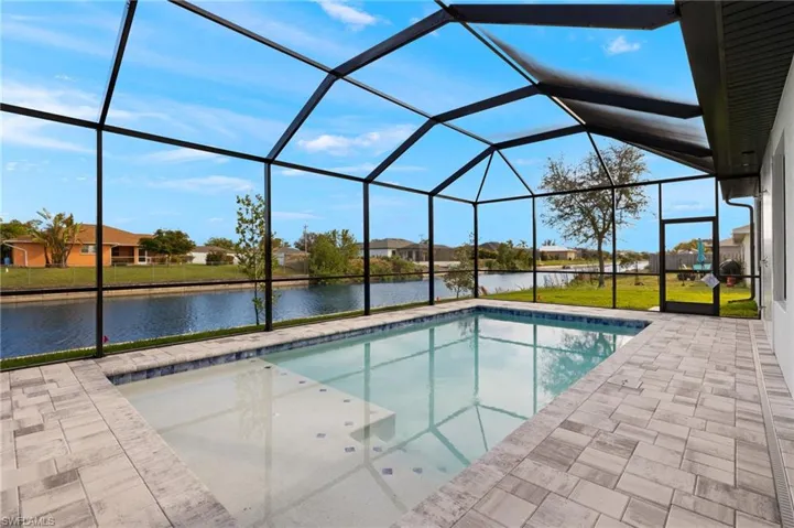View of pool with a lanai, a lawn, a water view, and a patio