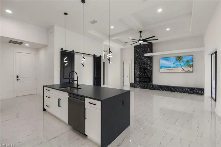 Kitchen with sink, black dishwasher, a barn door, decorative light fixtures, and white cabinets