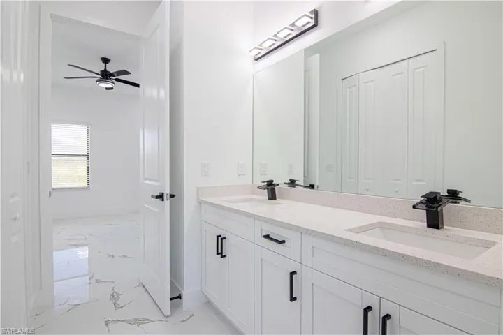 Bathroom with light marble finish flooring, double vanity, a closet, and a ceiling fan