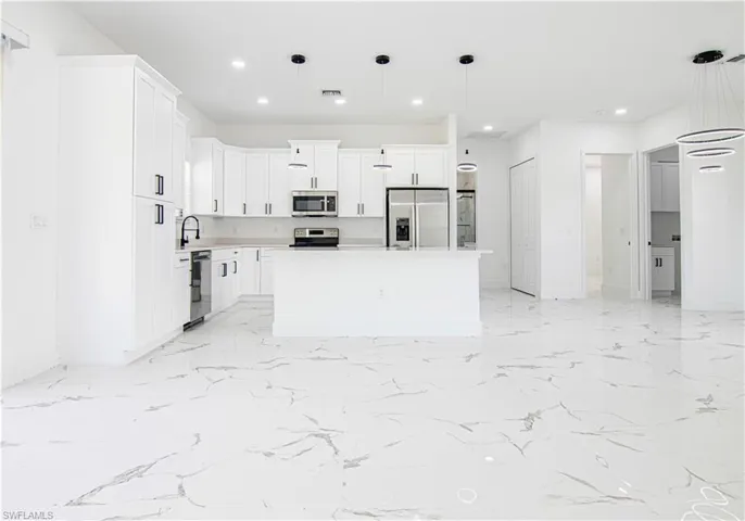 Kitchen with white cabinets, light countertops, decorative light fixtures, recessed lighting, and appliances with stainless steel finishes