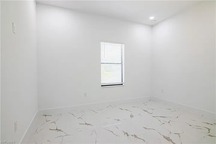 Empty room featuring light marble finish flooring and recessed lighting