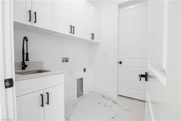 Washroom with washer hookup, cabinet space, light marble finish floors, and electric dryer hookup