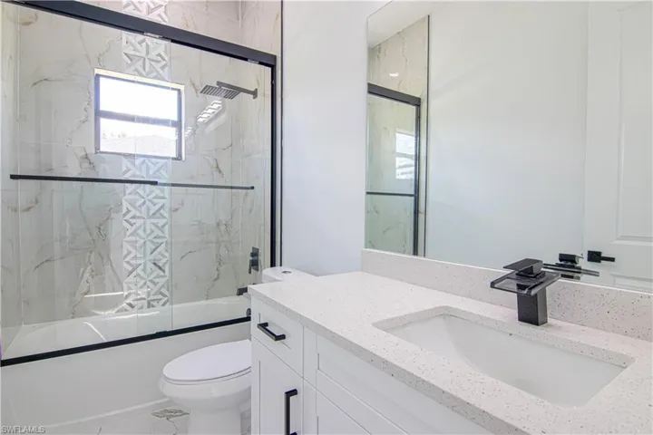 Bathroom with shower / bath combination with glass door and vanity