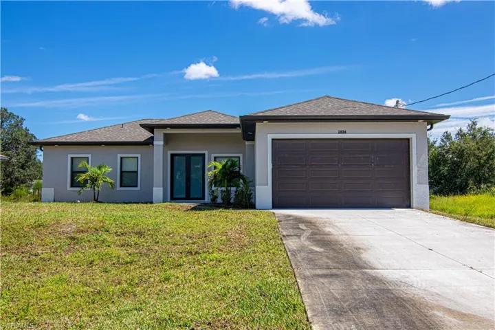 View of front of home featuring roof with shingles, driveway, stucco siding, a front lawn, and a garage