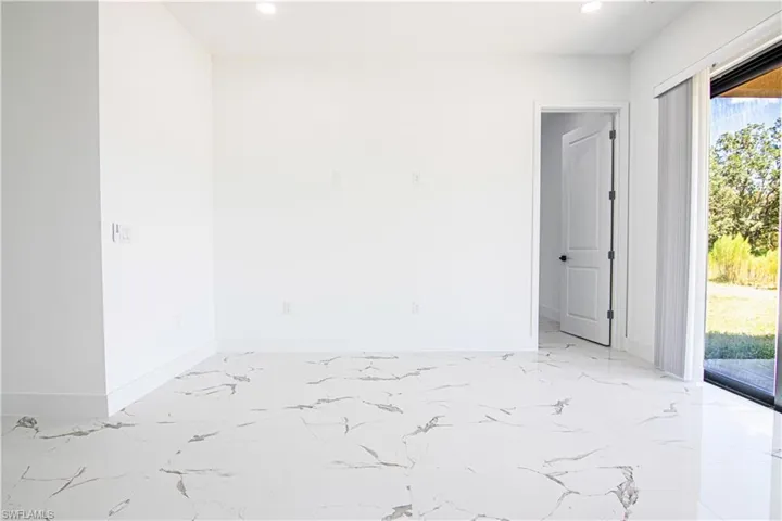 Empty room with light marble finish floors and recessed lighting