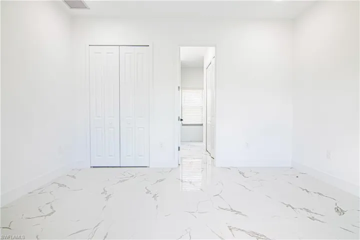 Unfurnished bedroom with light marble finish flooring, a closet, and connected bathroom