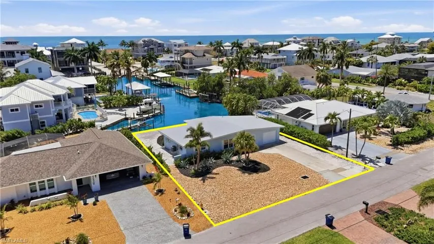 Aerial view showcasing the property's location within a coastal community, featuring nearby waterways and proximity to the beach with ocean views - Virtually Edited Image