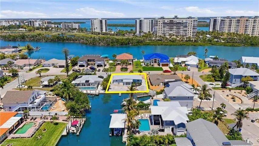 Waterfront property featuring a private boat dock, a paved driveway, and mature landscaping - Virtually Edited Image