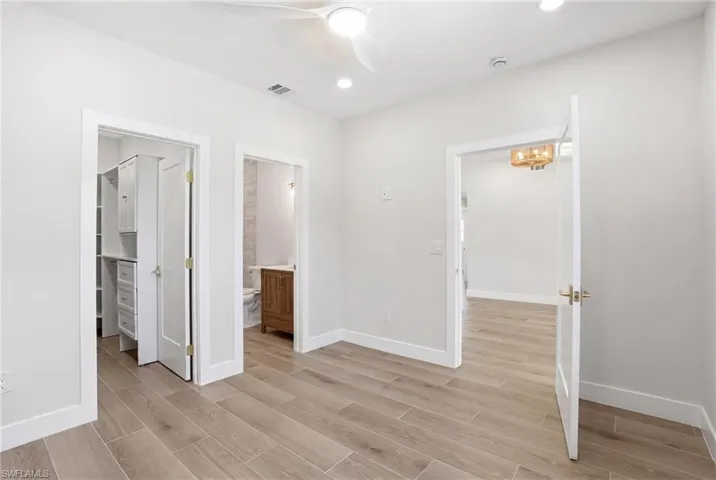 This room features light-colored tile flooring, a ceiling fan with integrated lighting, and recessed ceiling lights - Virtually Edited Image