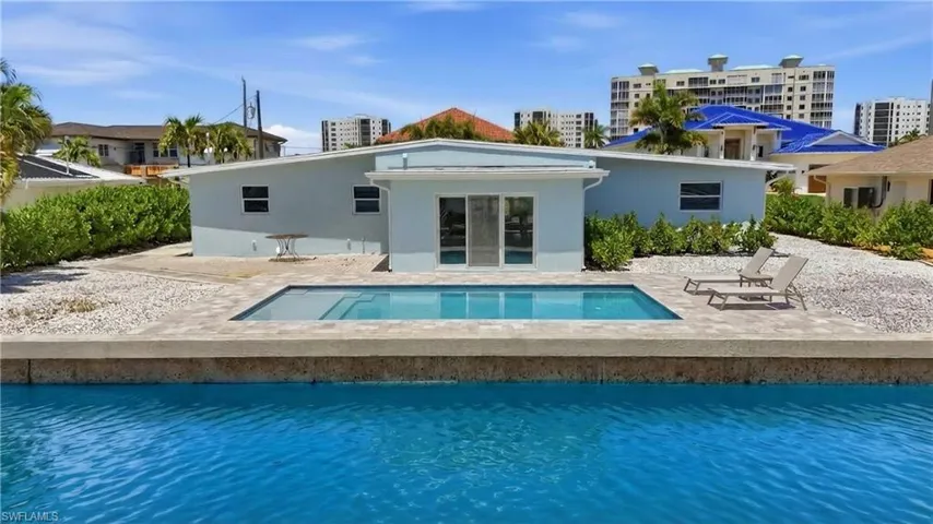 The property features room for a private swimming pool with a paved surround, lush perimeter landscaping, and a blue exterior - Virtually Edited Image