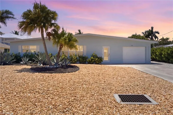 The property features a light blue exterior, a white garage door, and a well-maintained gravel yard - Virtually Edited Image
