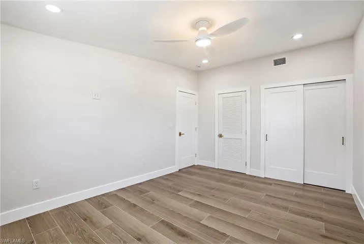 This room features wood-look tile flooring, bright white walls, and recessed lighting - Virtually Edited Image