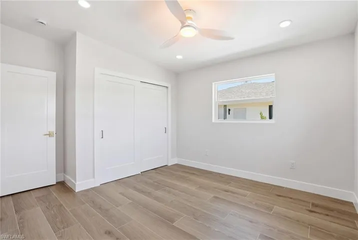 The room features light-toned wood-look flooring, a modern ceiling fan with lighting, and recessed lighting - Virtually Edited Image