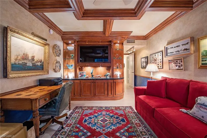 Home office featuring a textured wall, coffered ceiling, and light wood-style flooring