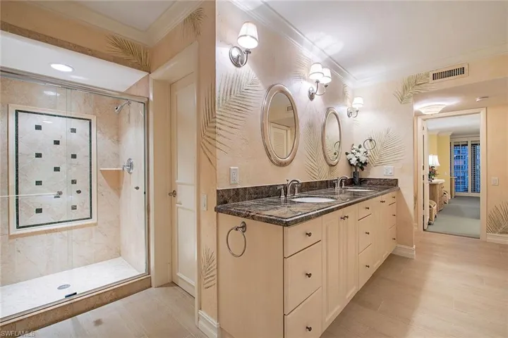 Full bathroom featuring ornamental molding, double vanity, a stall shower, and light wood finished floors