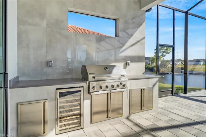 View of patio / terrace featuring a lanai, an outdoor kitchen, a sunroom, and beverage cooler