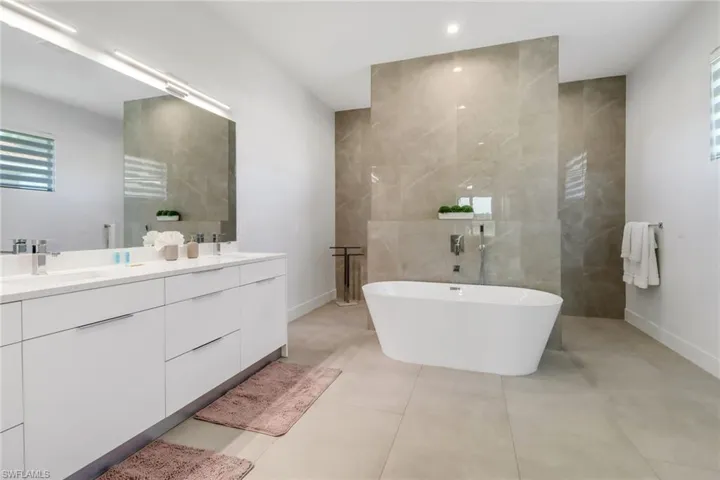 Bathroom with a freestanding tub, double vanity, a towel warming rack, and walk in shower